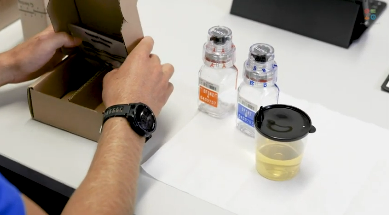 Athlete preparing to divide urine sample between two small beakers at doping control station