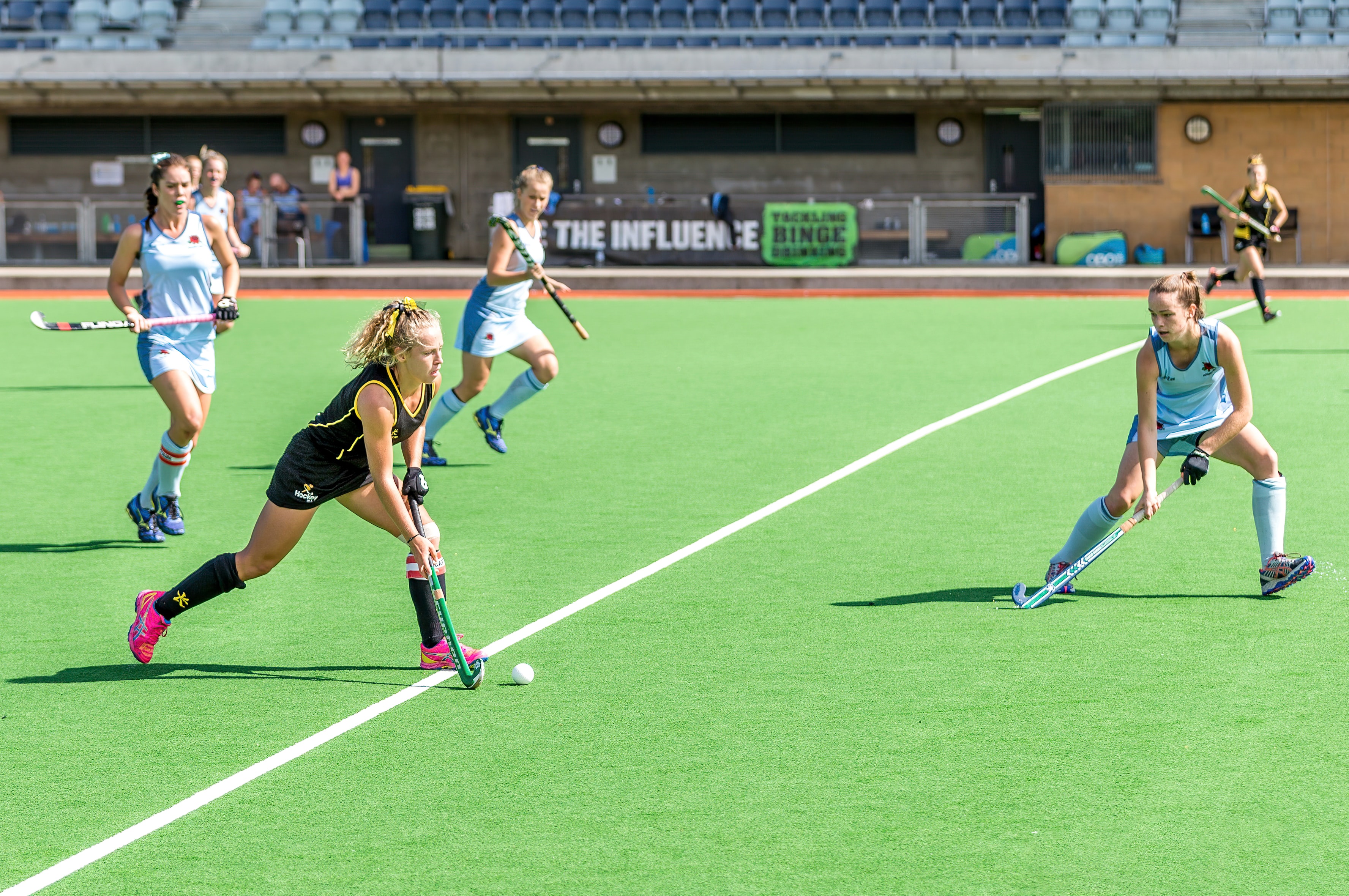 Players chase the ball in a women's hockey match.