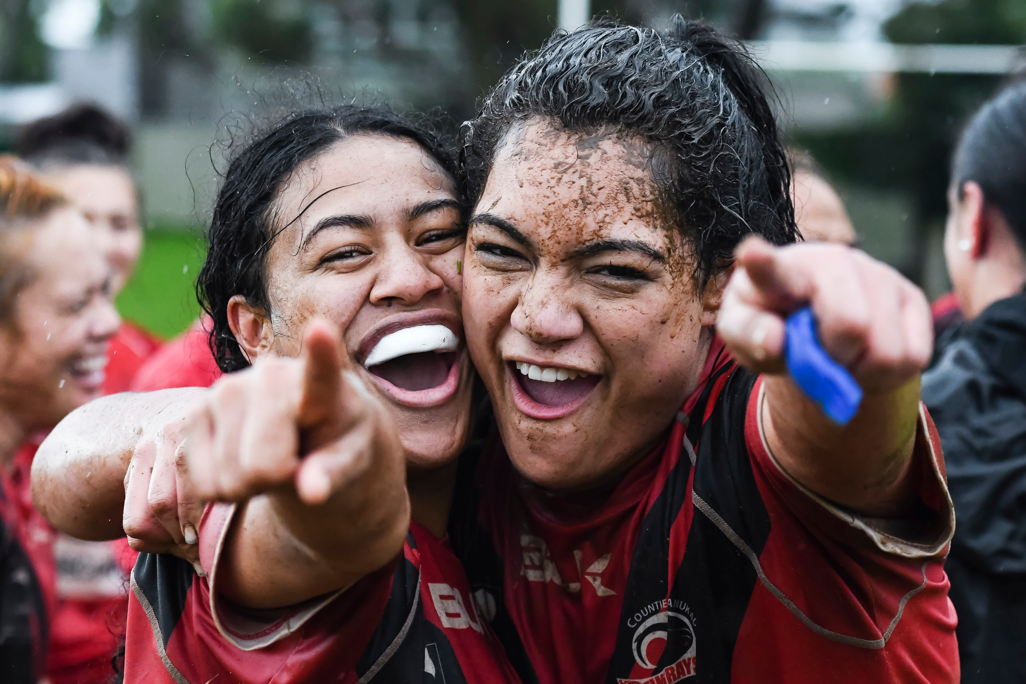 Two female rugby athletes cheer and point to camera